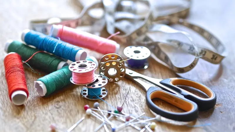 Spools of thread and a pair of scissors on a work bench